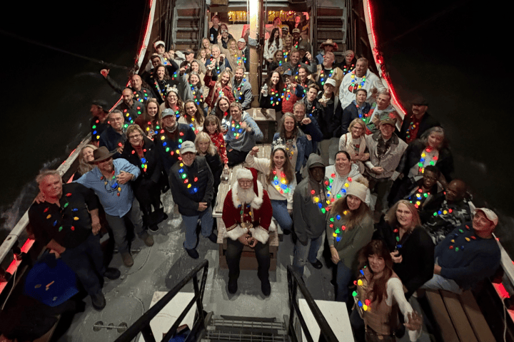 Group on outdoor staircase, wearing holiday lights, with Santa in the center.