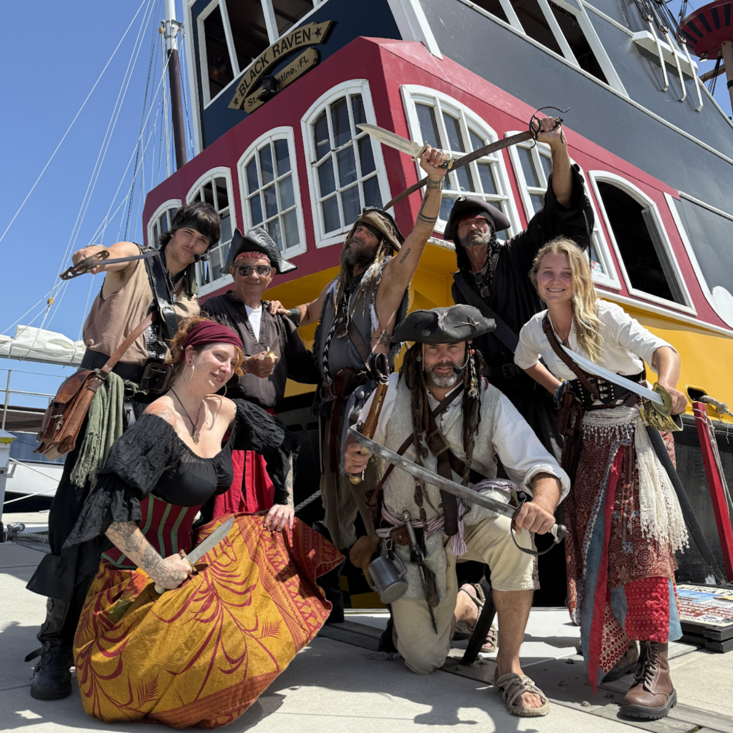 Group of people dressed as pirates posing in front of a pirate-themed ship.