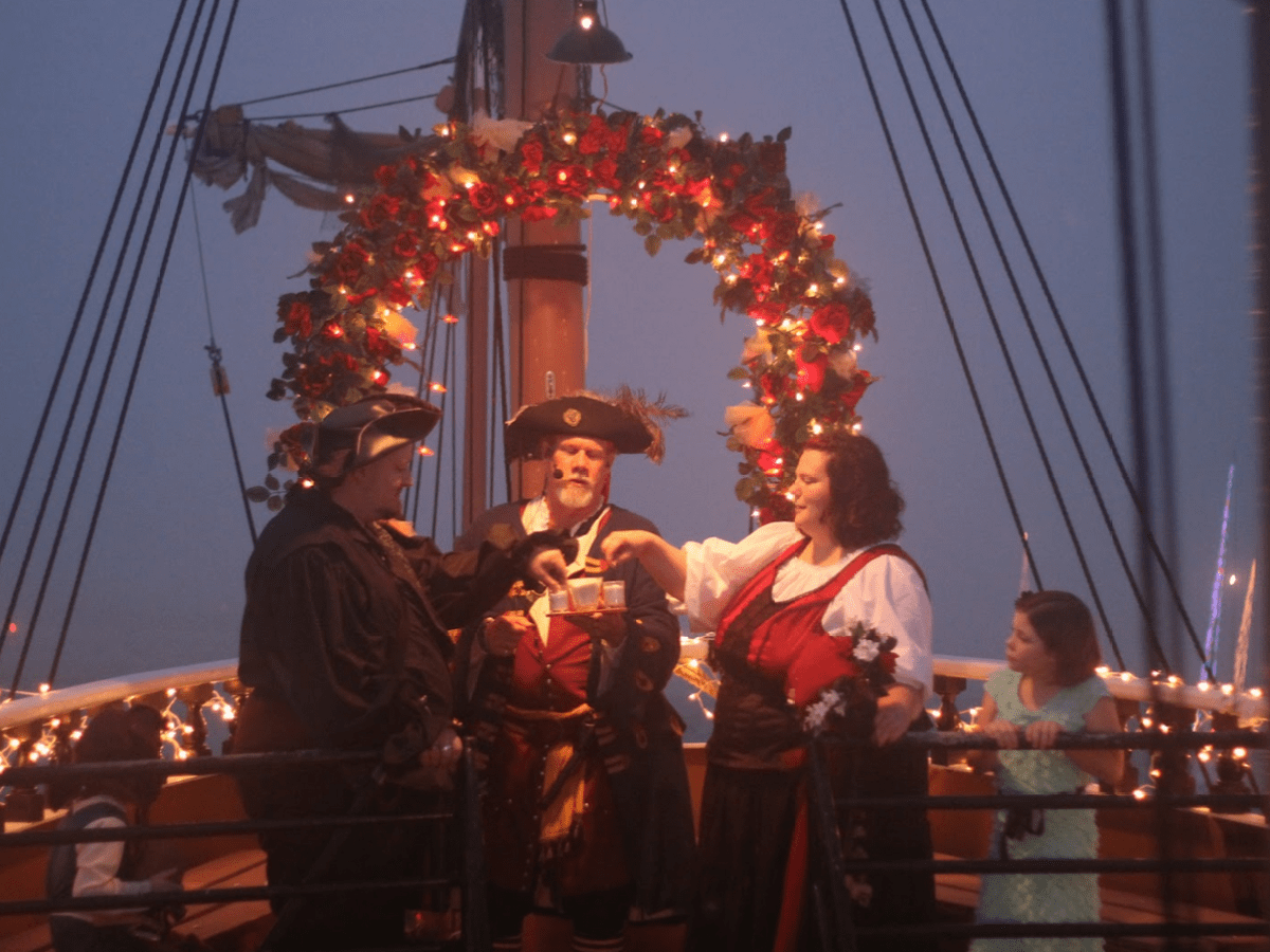 Costumed group on decorated ship with lights and arch.